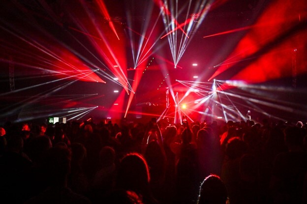 Panasonic laser projectors illuminate a Cold War Kids concert with red and white lights, while a crowd cheers in the audience.
