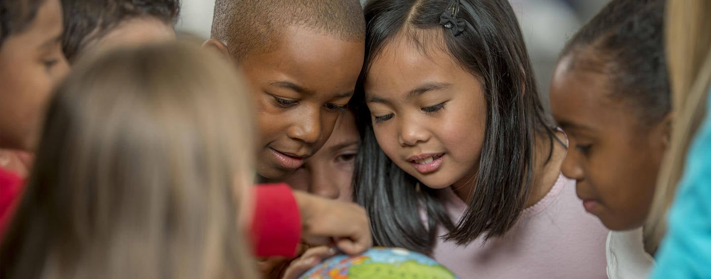 Children pointing on a globe