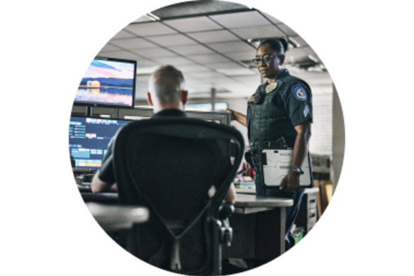 Two police officers in an office in front of computers