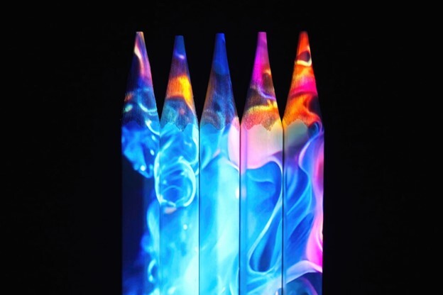 A 4k projector creates an abstract display on four colored pencils, demonstrating projection mapping technology.