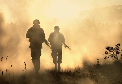 Two soldiers navigate the field with the help of military technology.