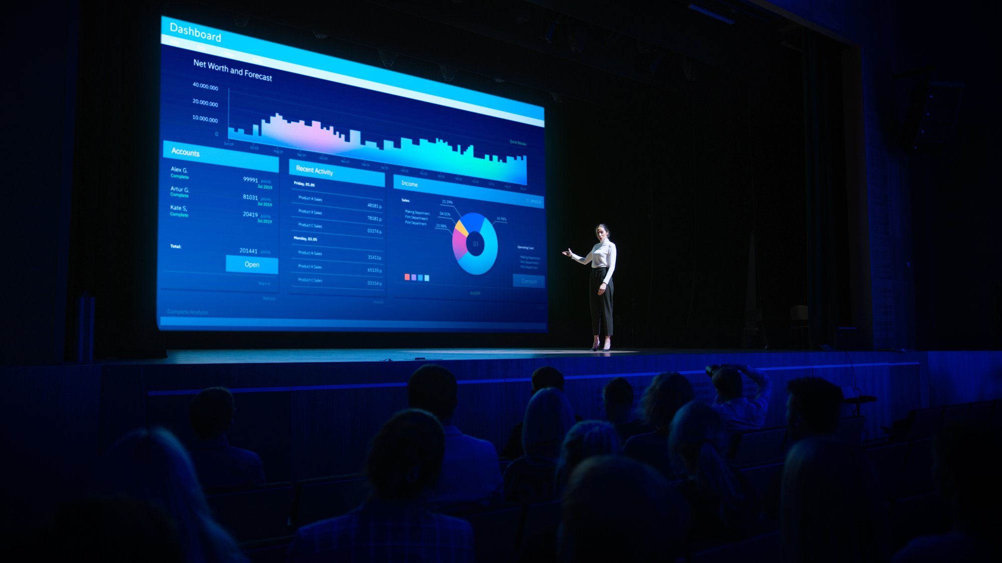 woman speaking in front of large display at business conference