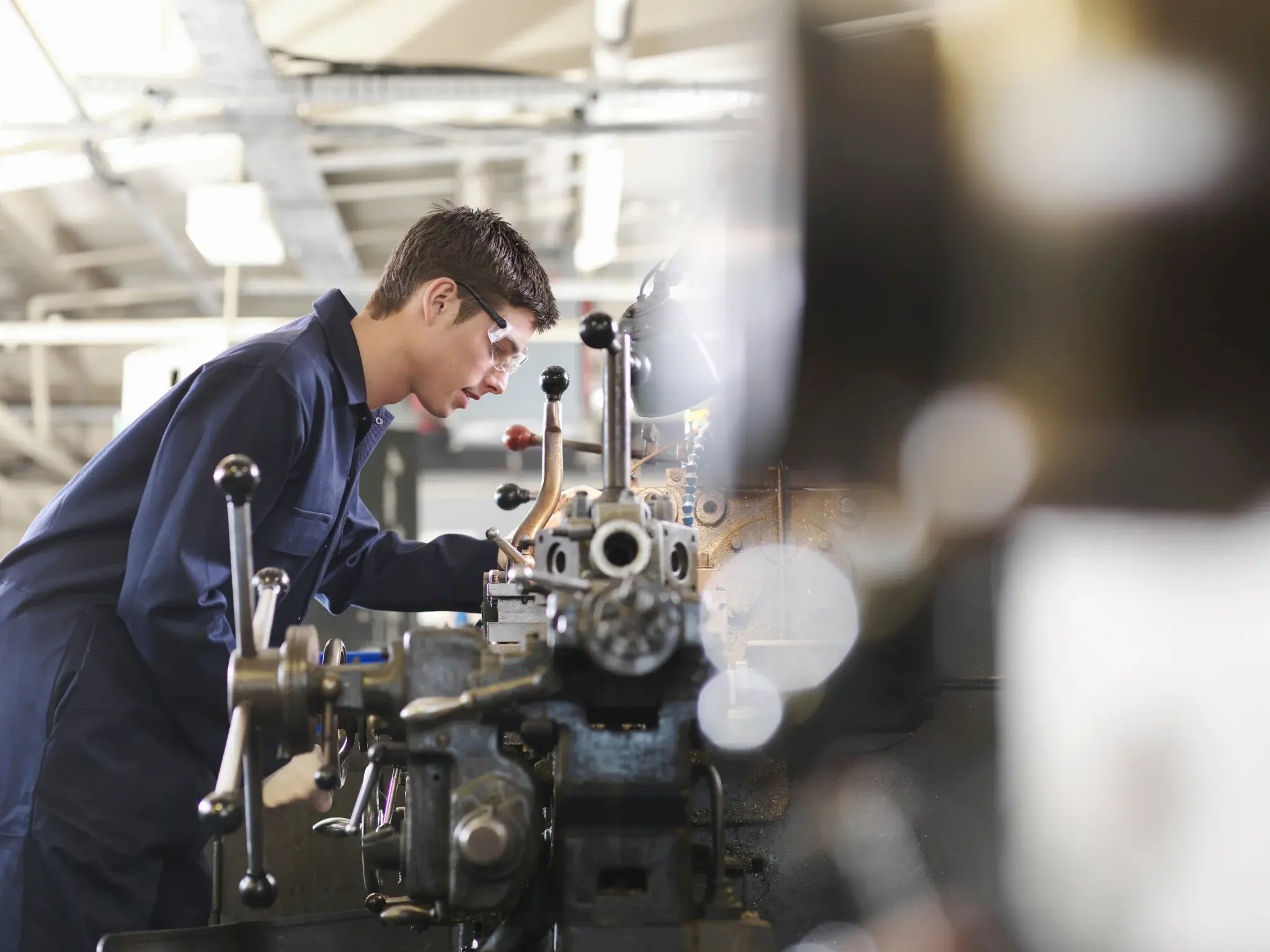 Factory worker inspecting industrial machinery on a production line to support manufacturing efficiency and operational reliability.