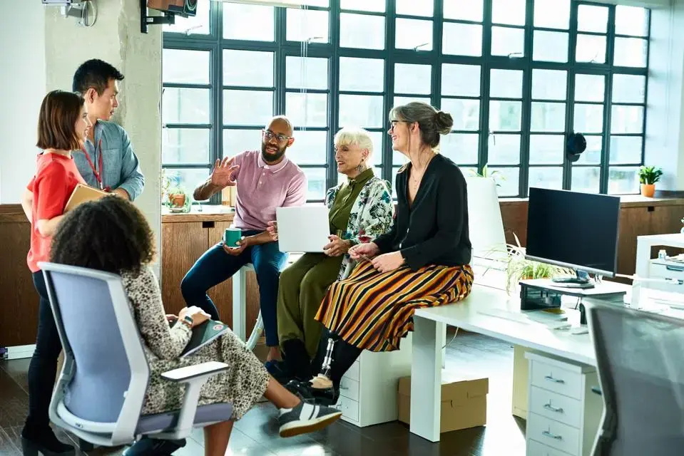 Business colleagues in meeting with female amputee sitting on desk