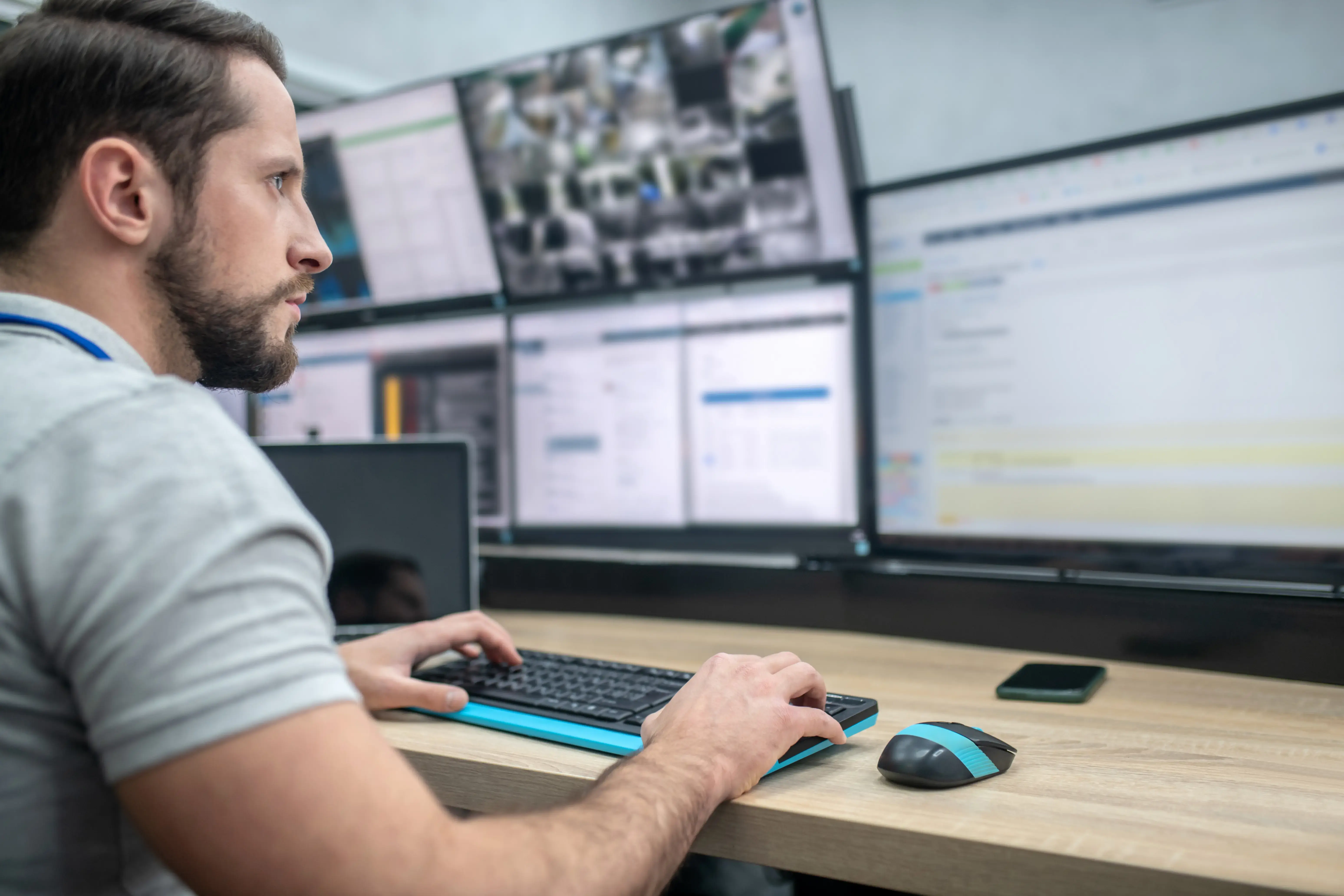 Attentive man with keyboard in front of computer screens