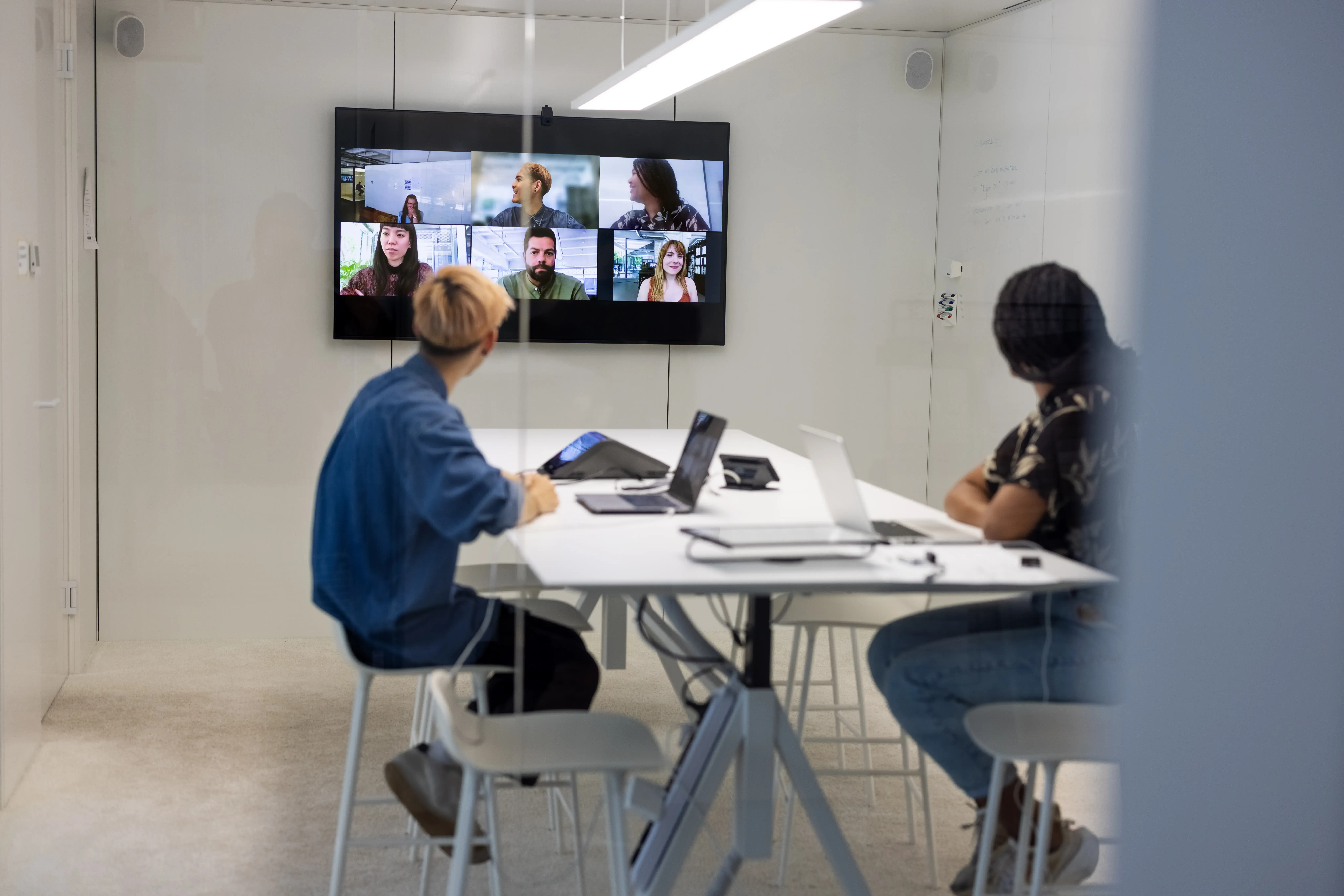 Business people sitting inside conference room having a video call