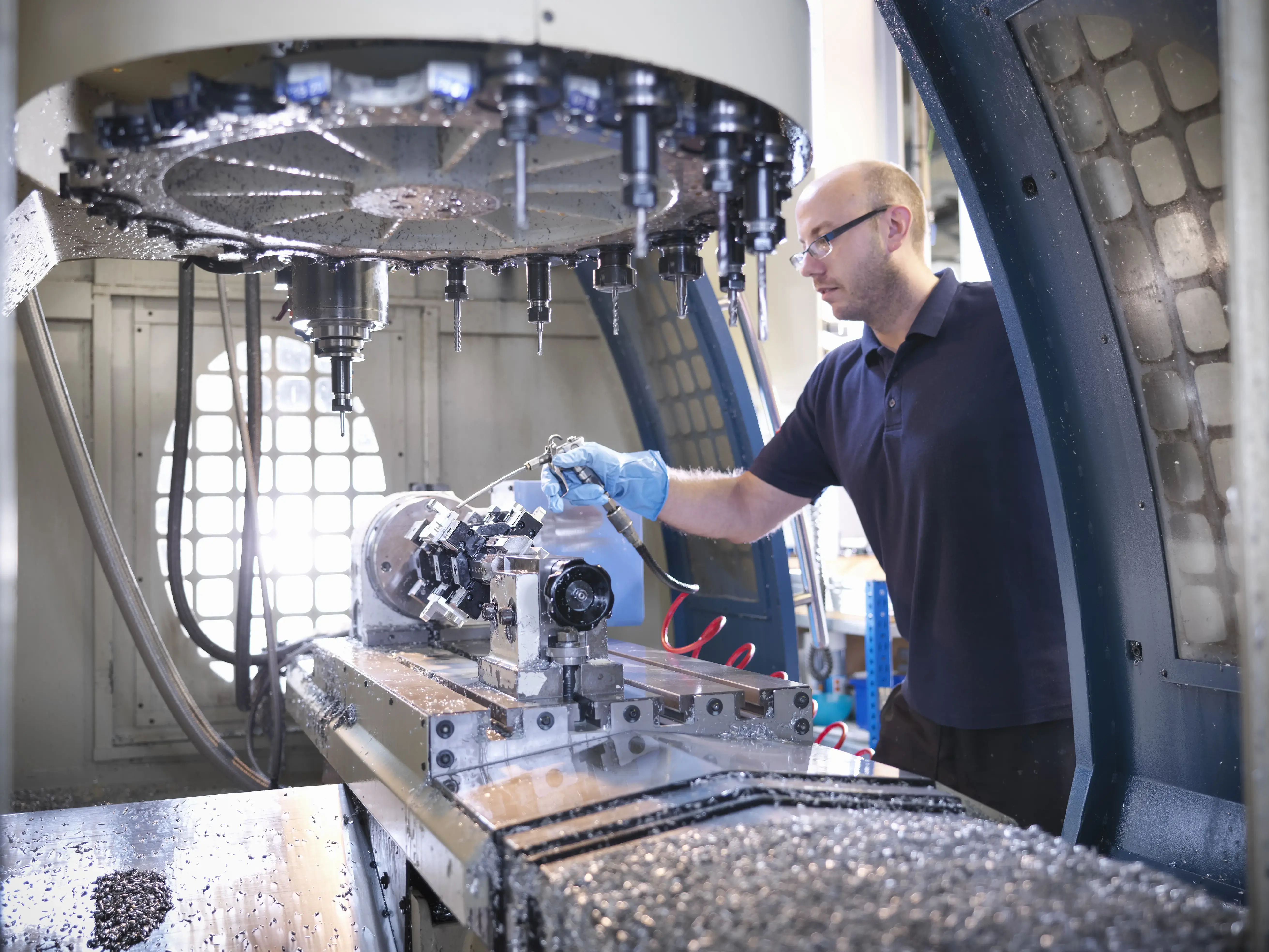 Engineer cleaning computer numerical controlled (CNC) lathe in factory