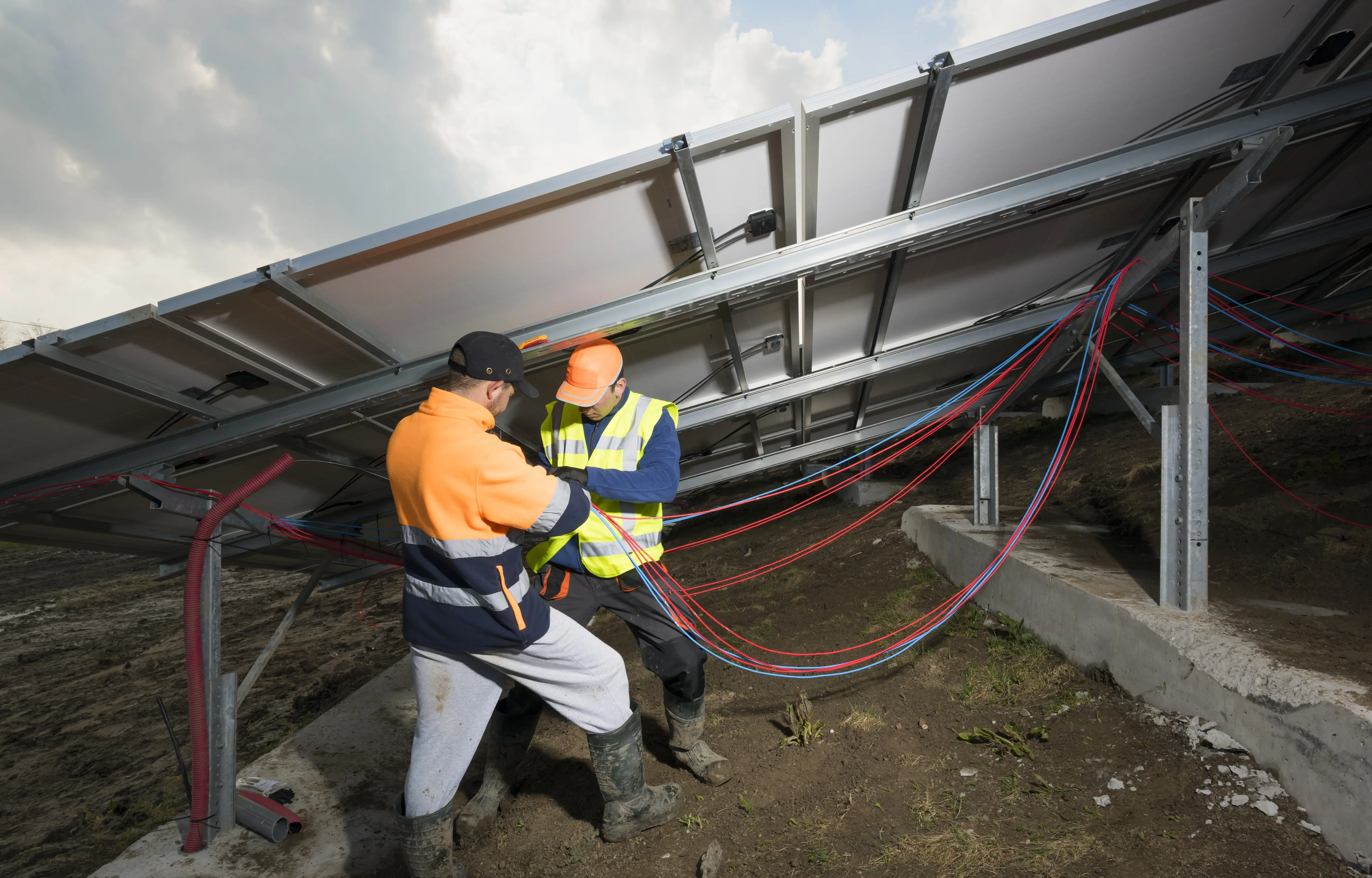 Engineers connecting solar panels on new solar farm, situated on former waste dump