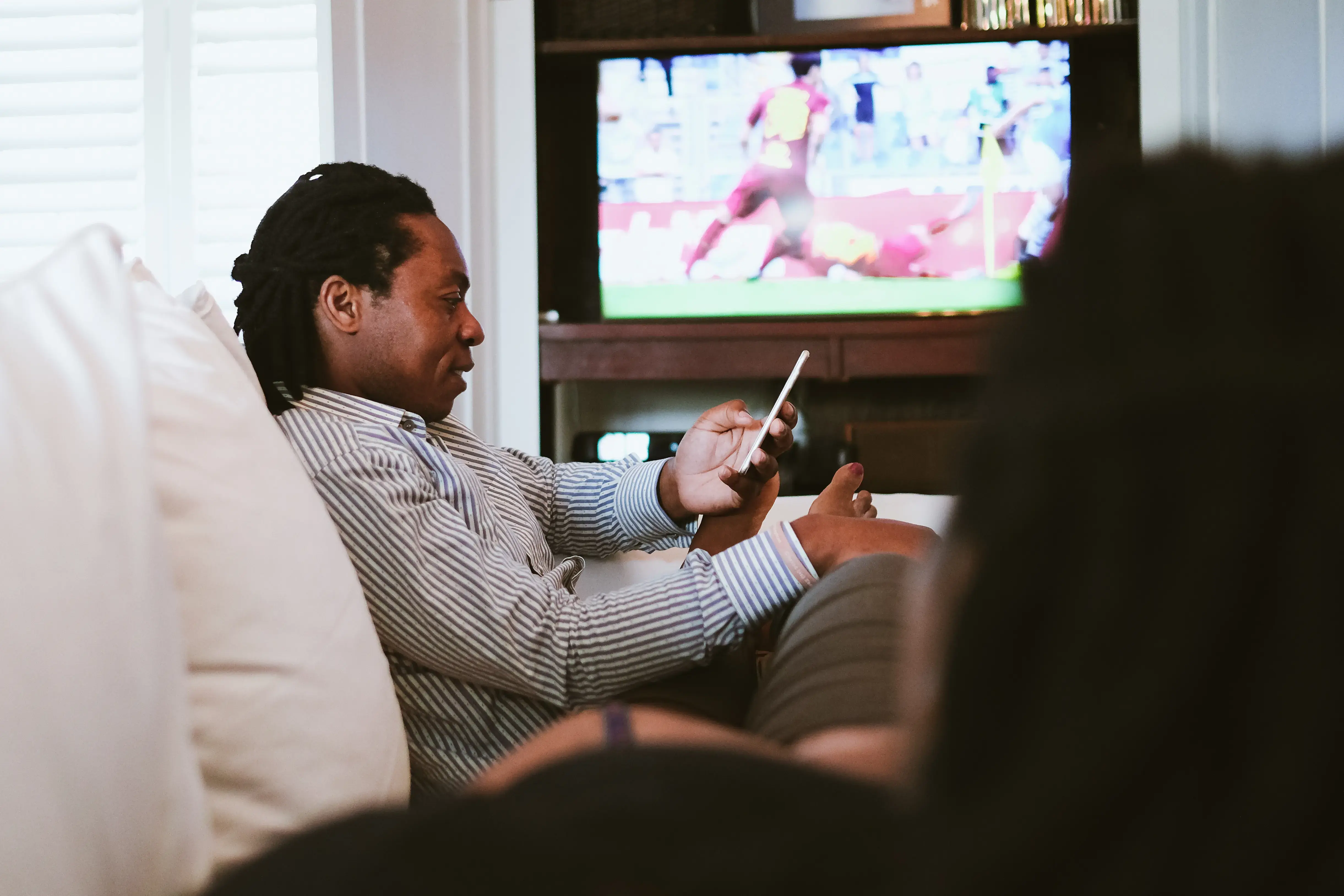 Father texting whilst mother watches sport on TV